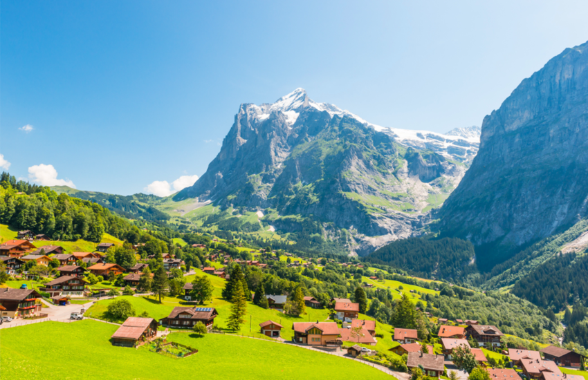 Town of Grindelwald on green landscape with huge mountain in background 