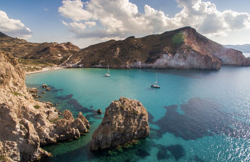 Two boats in clear water in bay of Milos island