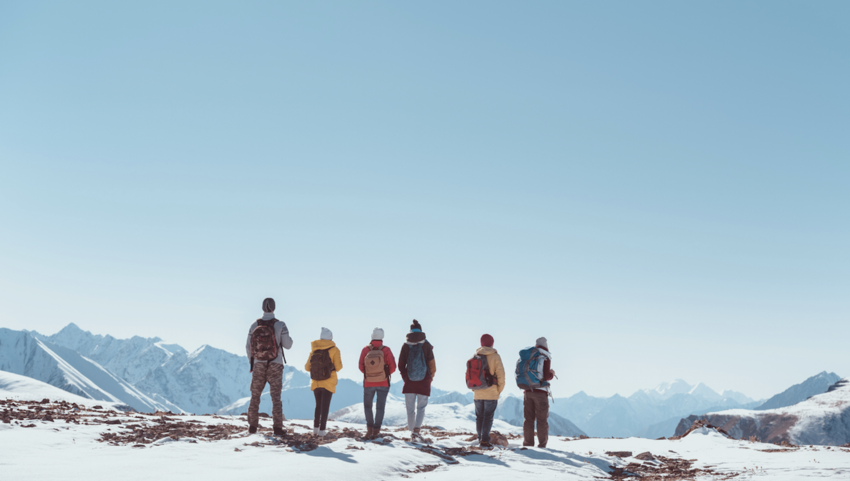 Group of backpackers standing at the top of a snowy mountain peak