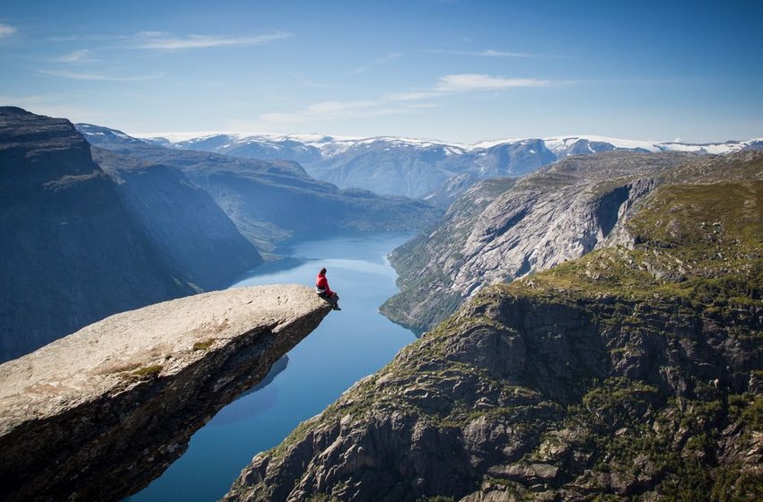 Person sitting on edge of Trolltunga cliff