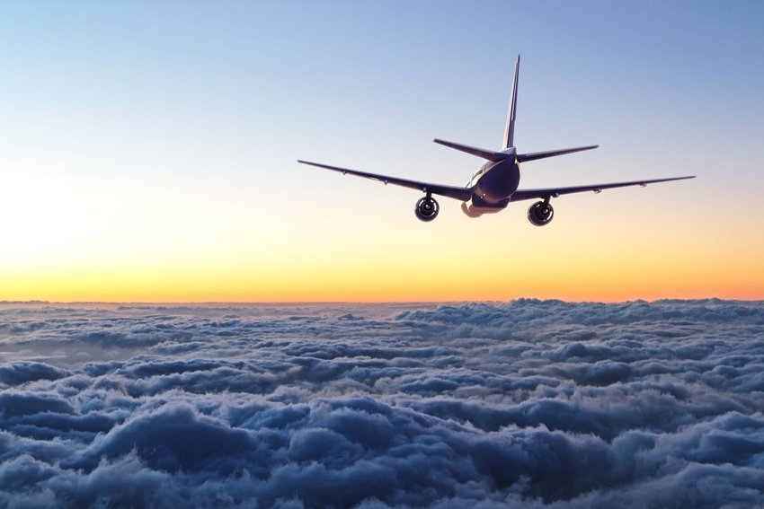 Commercial airplane flying above clouds with sunset