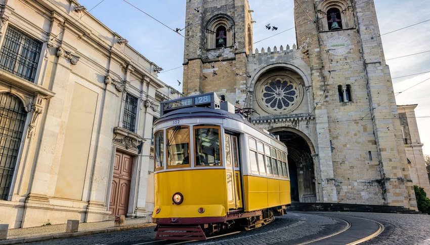 Yellow tram in front of Santa Maria cathedral in Lisbon, Portugal
