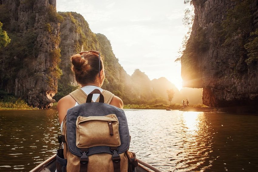 Woman sitting on front of boat with backpack on in Tam Coc, North of Vietnam