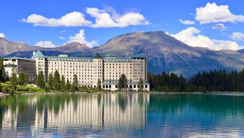 The Fairmont Chateau on Lake Louise with trees surrounding and mountains in background 