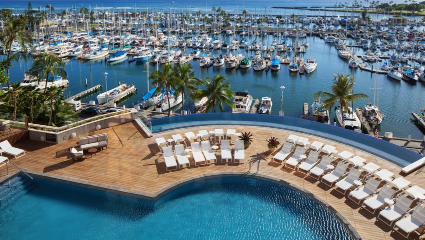 Edge of pool and wooden pool deck overlooking boat harbor and the ocean