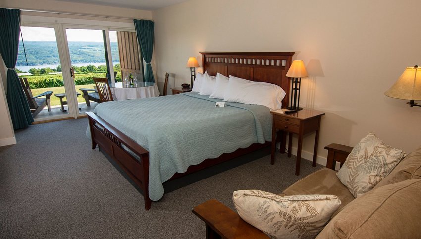 Interior of Guest Room with couch and bed, balcony looking out onto vineyard