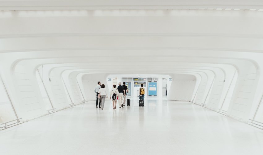 Group walking together through white hallway in airport