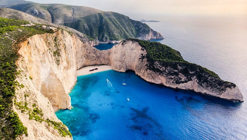 Aerial view of hidden beach with wrecked ship and huge cliffs surrounding