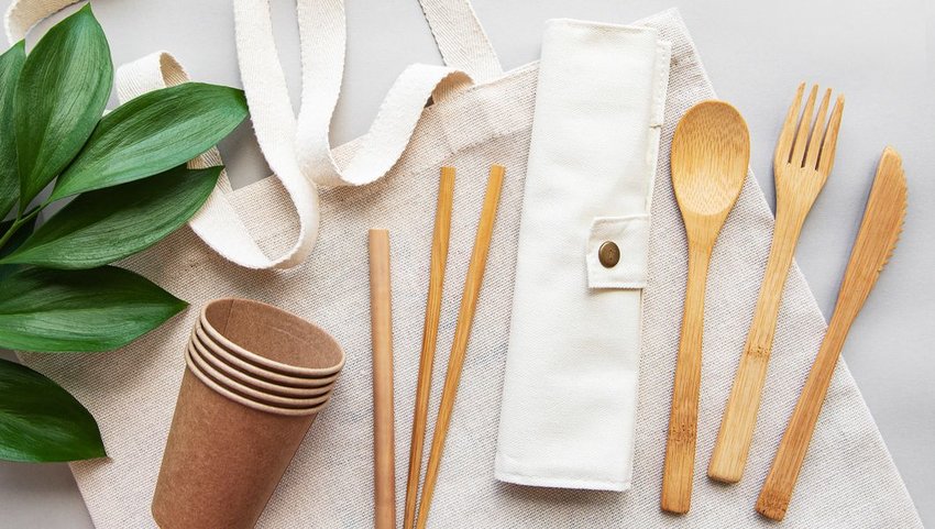 Bamboo eating utensils, straws and cups on a canvas bag