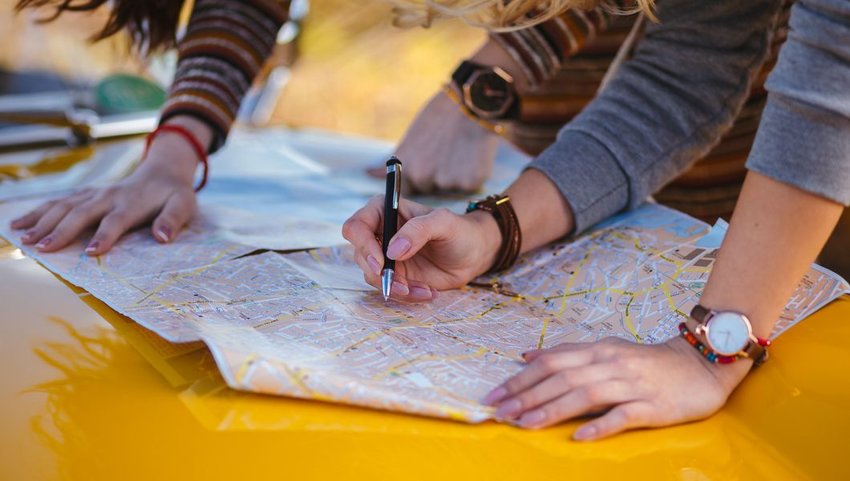 Two people looking at map on hood of car