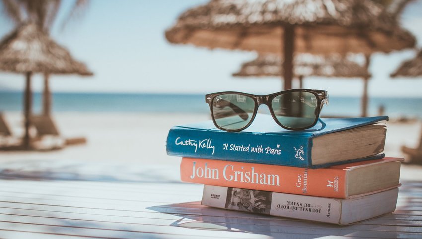 Stack of books with sunglasses on top at the beach