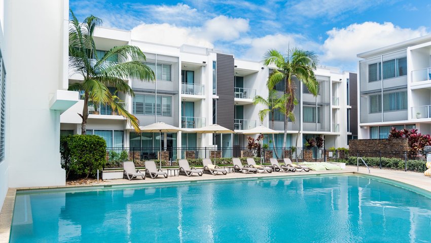 Exterior of hotel and pool with lounge chairs and palm trees