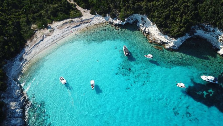 Aerial view of beach with boats in bright blue water