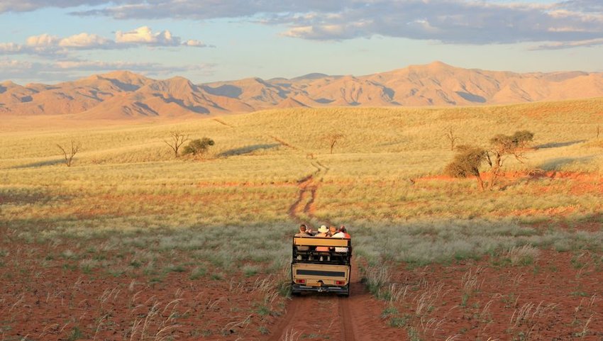 Tourists driving down road towards mountain range