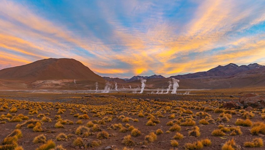 El Tatio geyser with mountains in distance at sunset