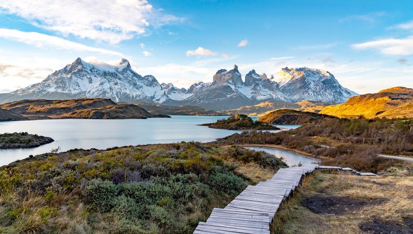 Wooden hiking path with snowy mountains in background