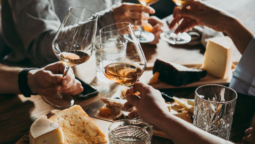 People drinking wine with cheese on boards