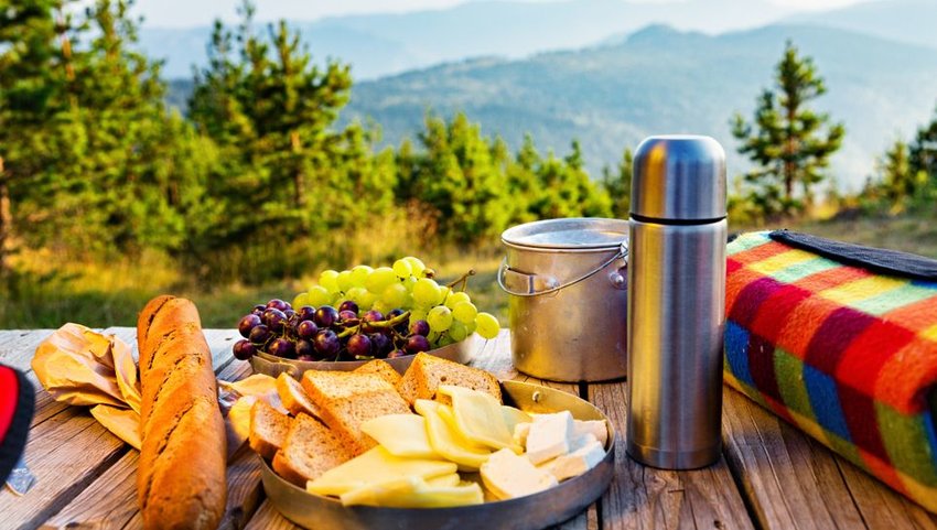 Picnic on wooden table with trees and mountains in background