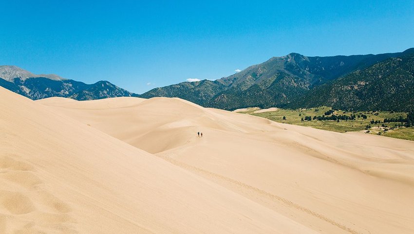 Two people walking on a sand dune in the distance at Great Sand Dunes National Park and Preserve