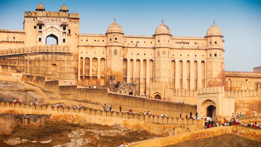 Amber Fort in morning light with tourists walking up pathways in Jaipur