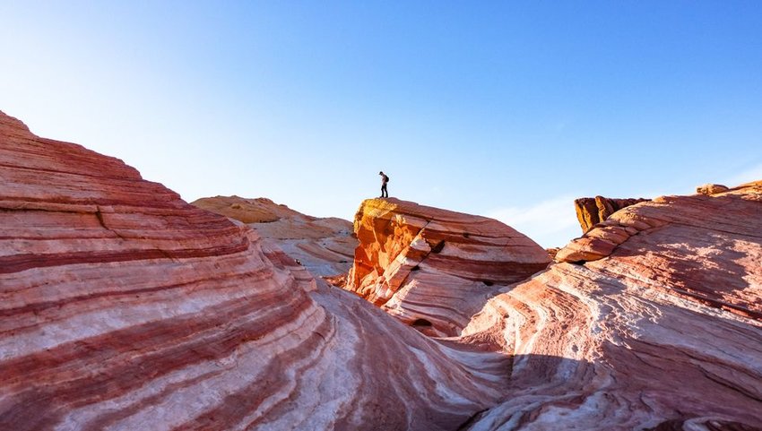 A hiker standing on rocks of Fire Wave in Valley of Fire State Park, Nevada