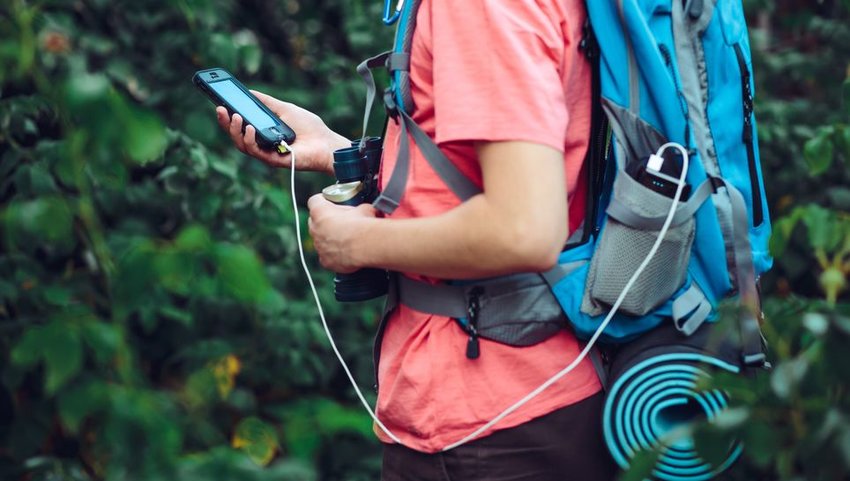 Person hiking with phone plugged into a portable charger