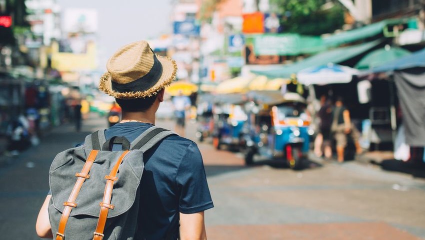 Tourist with backpack and hat standing in street