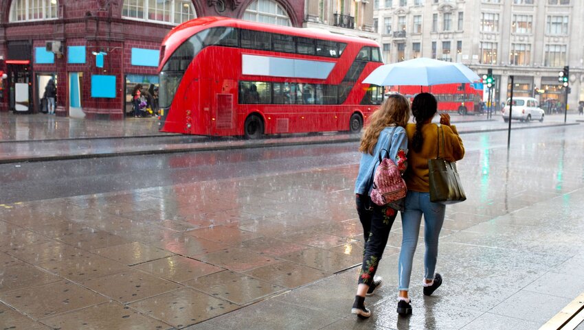 Two women sharing an umbrella in the London rain.