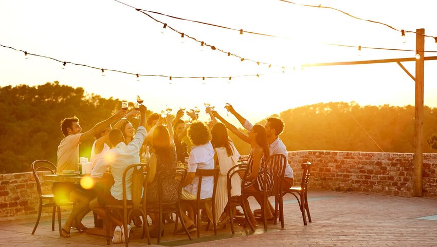 A group of friends cheering with wine at sunset. 