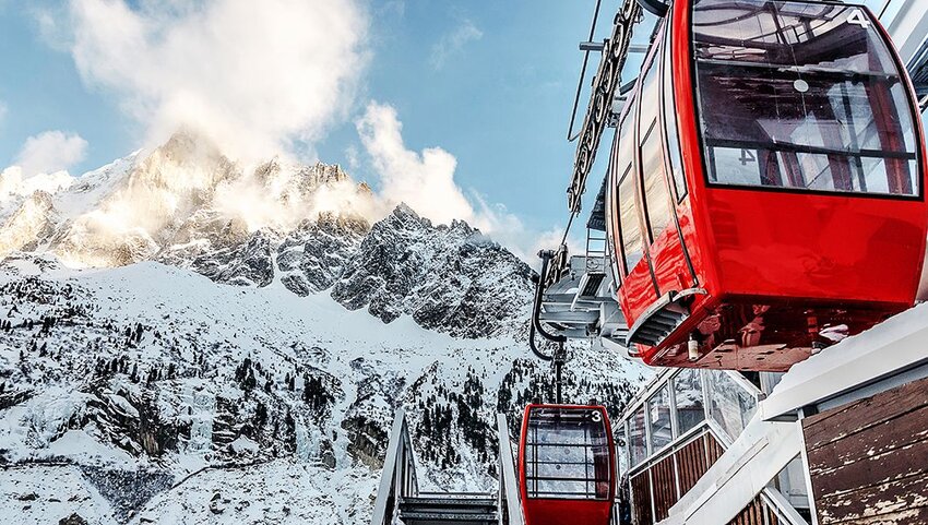 Red cable cars with snowy mountain in background. 