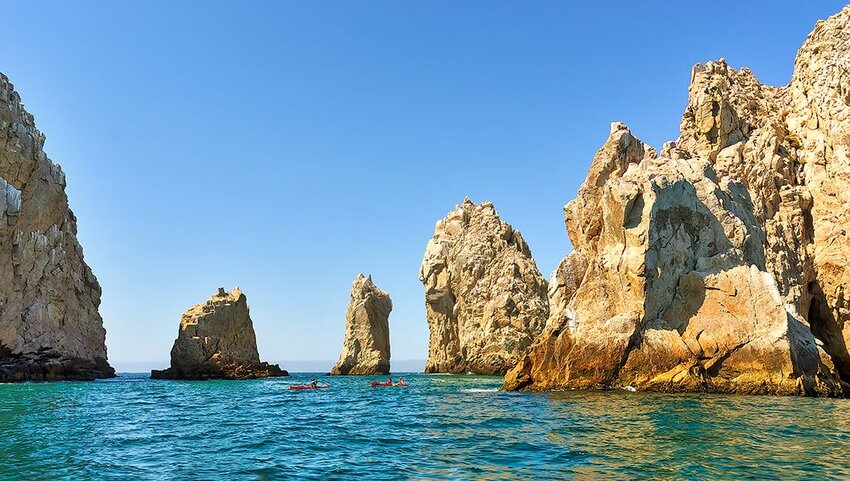 Kayakers paddling through rock formations.