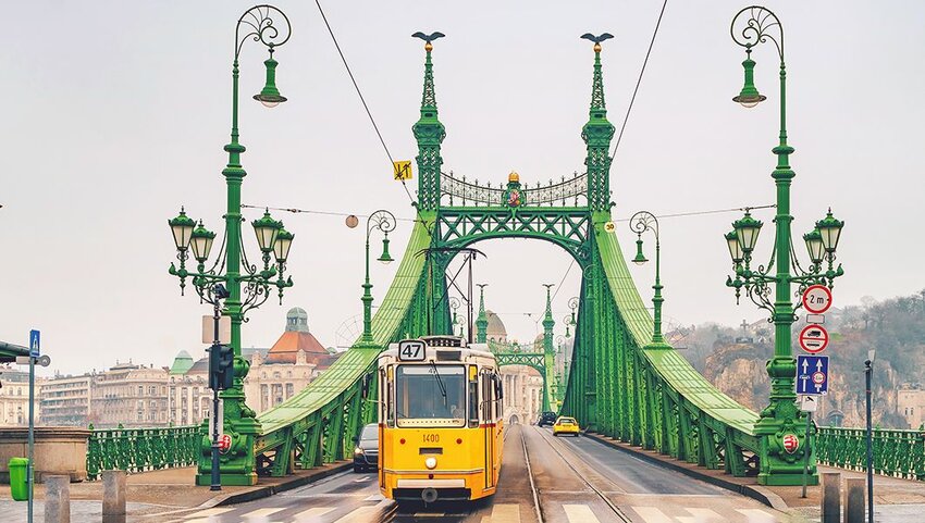 Yellow tram crossing bridge.
