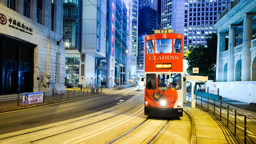 Tramcar riding down street at night in Hong Kong.