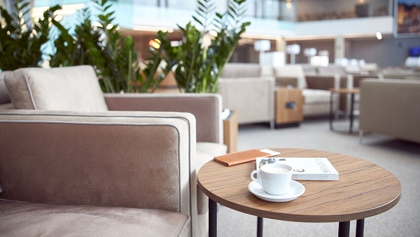 Round table with book, coffee cup, and wallet next to armchair in airport lounge. 