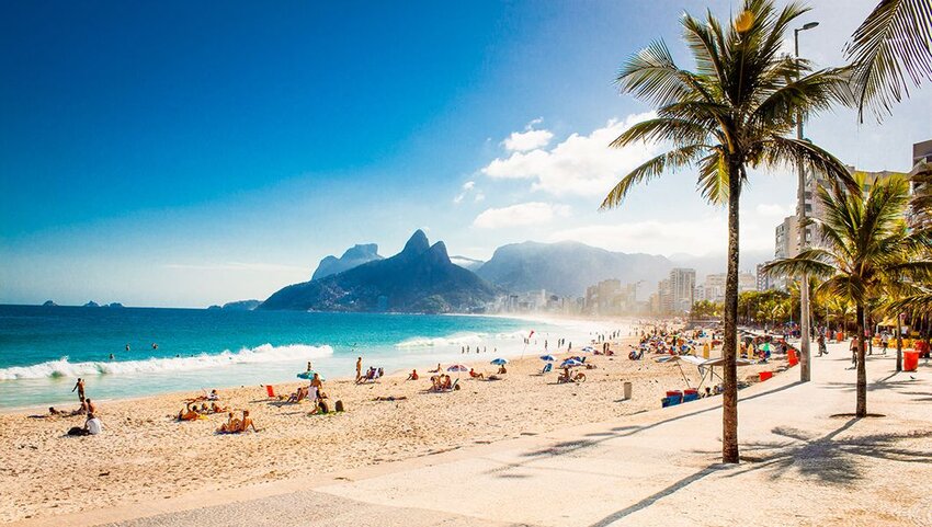 People on Ipanema beach in Rio de Janeiro with Two Brothers Mountain in the distance. 