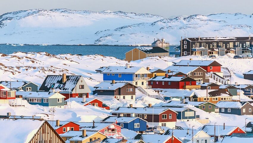 Nuuk, Greenland covered in snow with sea and mountains in the background.