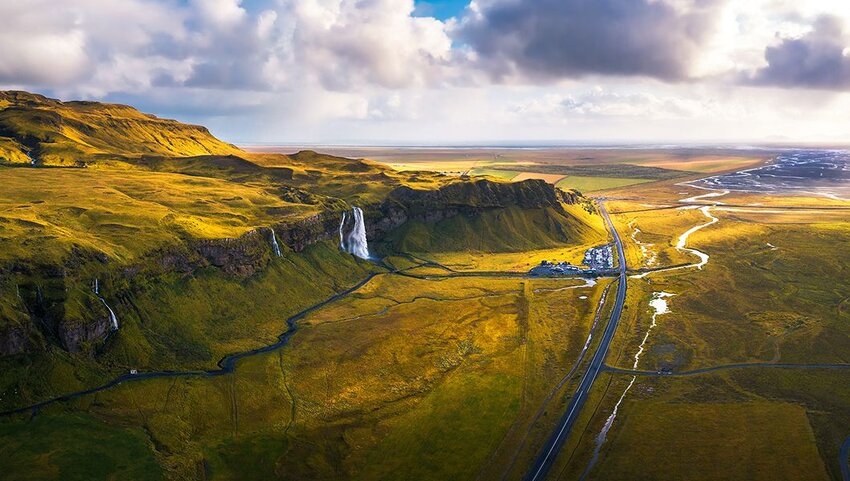 Aerial view of Seljalandsfoss Waterfall, Seljalands River, and the ring road in Iceland at sunset.