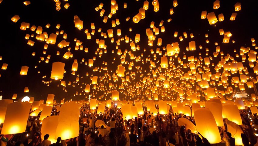 People releasing floating lanterns into night sky.