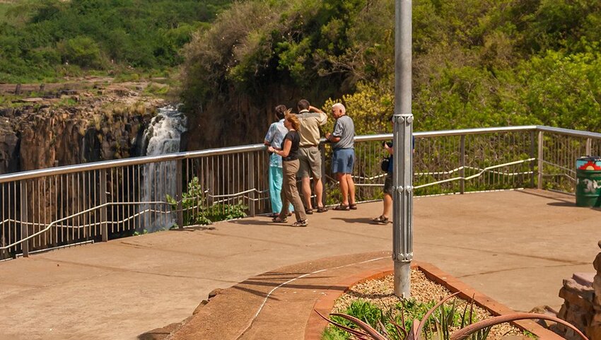 Group of people at metal fence looking out over Olo’upena Falls.