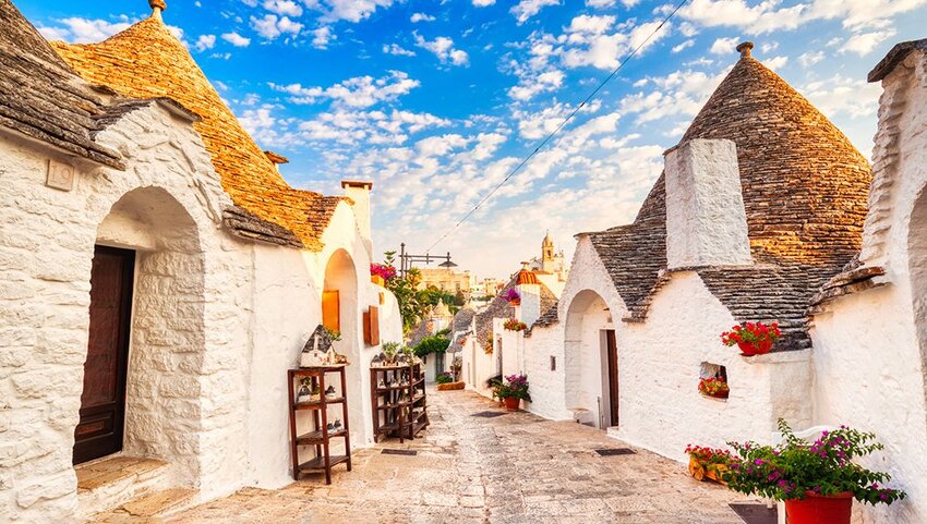 White cone-shaped trulli houses lining street in Alberobello, Puglia, Italy.