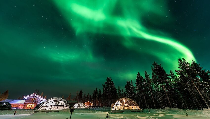 Green northern lights over glass igloos. 