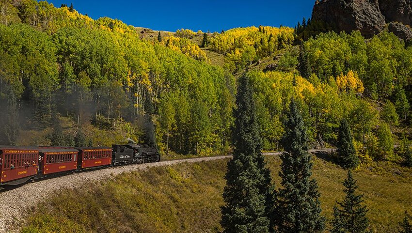 The Cumbres and Toltec Scenic Railroad steam train traveling through scenic landscape. 