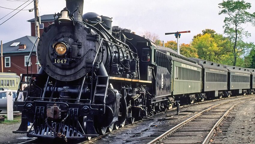Black steam train leaving a station.