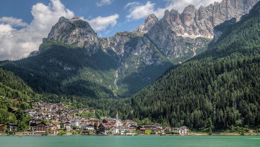 Town next to river with mountains behind it. 