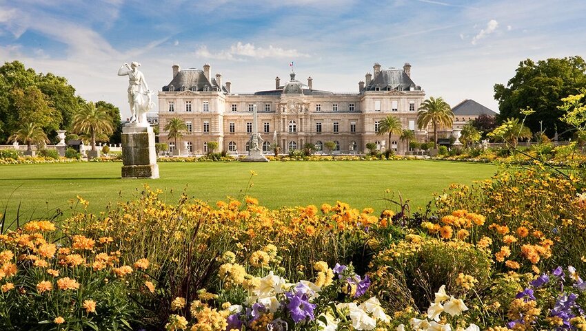 Jardin du Luxembourg with the Palace and statue with flowers in front and blue sky behind.