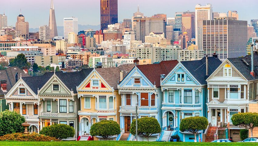 Row of Painted Ladies houses with skyscrapers in distance. 