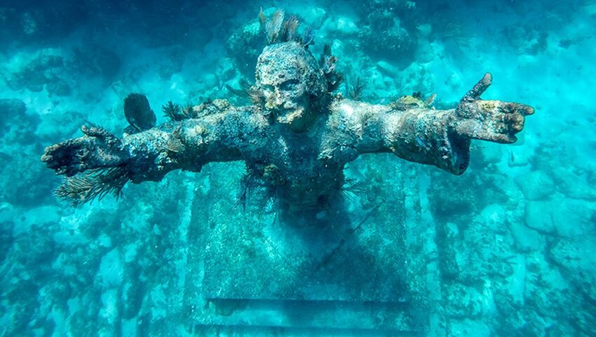 Underwater statue of Jesus with his arms outstretched.