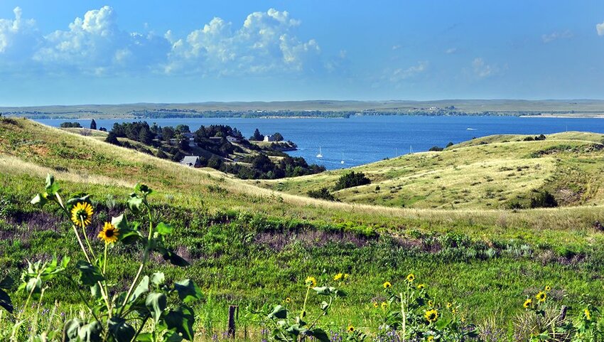 Rolling Nebraska grassland slopes down to blue, Lake McConaughy.