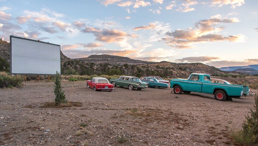 Vintage cars parks in front on movie screen.