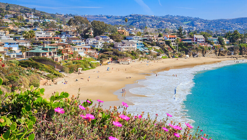Crescent Bay of Laguna Beach, with people on beach and houses along the shore.